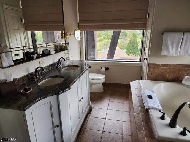 a bathroom with a granite countertop sink a toilet a mirror and window