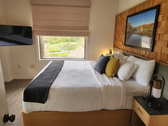 a bedroom with a bed and a flat tv screen on dresser