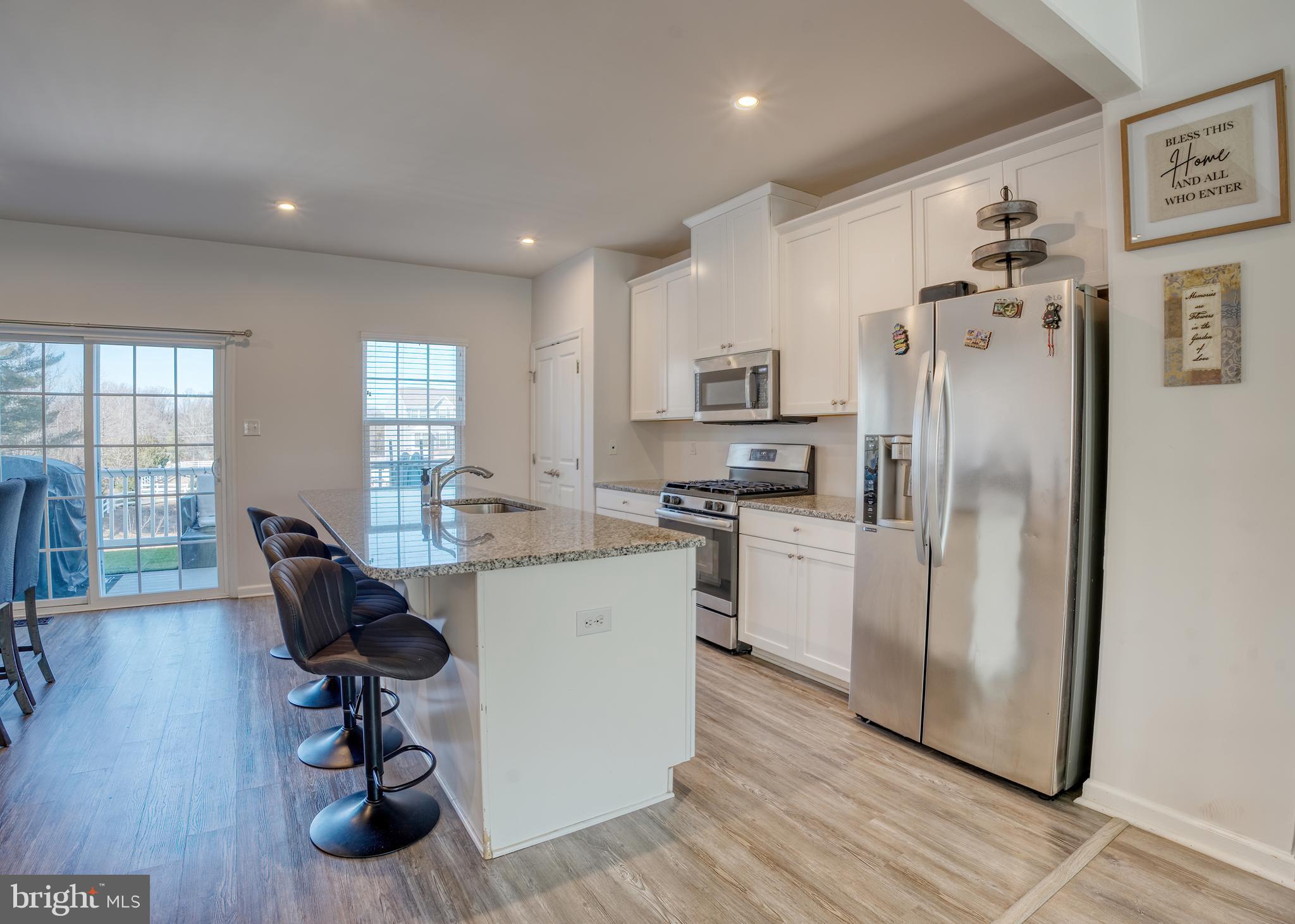 133 Spire Place Sewell, NJ 08080 - Photo 19 of 49 a kitchen with a refrigerator a stove a sink cabinets and a dining table with wooden floor