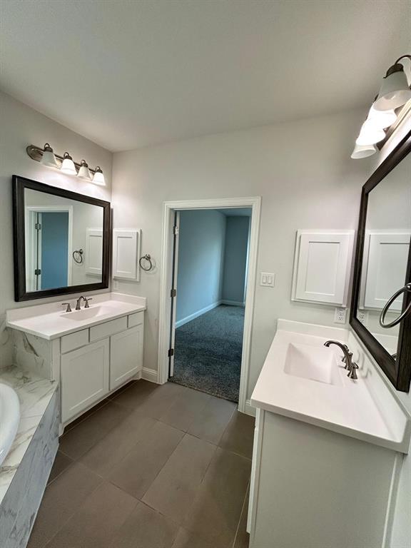 1704 Dunbrook Road McKinney, TX 75071 - Photo 11 of 17 Bathroom with two vanities, a bath, and dark tile patterned floors