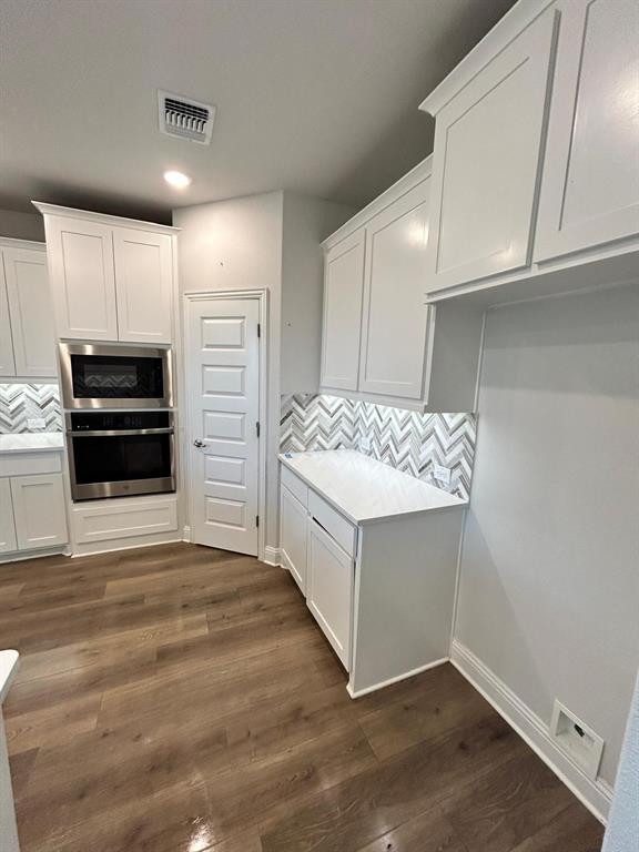 1704 Dunbrook Road McKinney, TX 75071 - Photo 6 of 17 Kitchen featuring decorative backsplash, white cabinetry, stainless steel appliances, dark wood-style floors, and recessed lighting