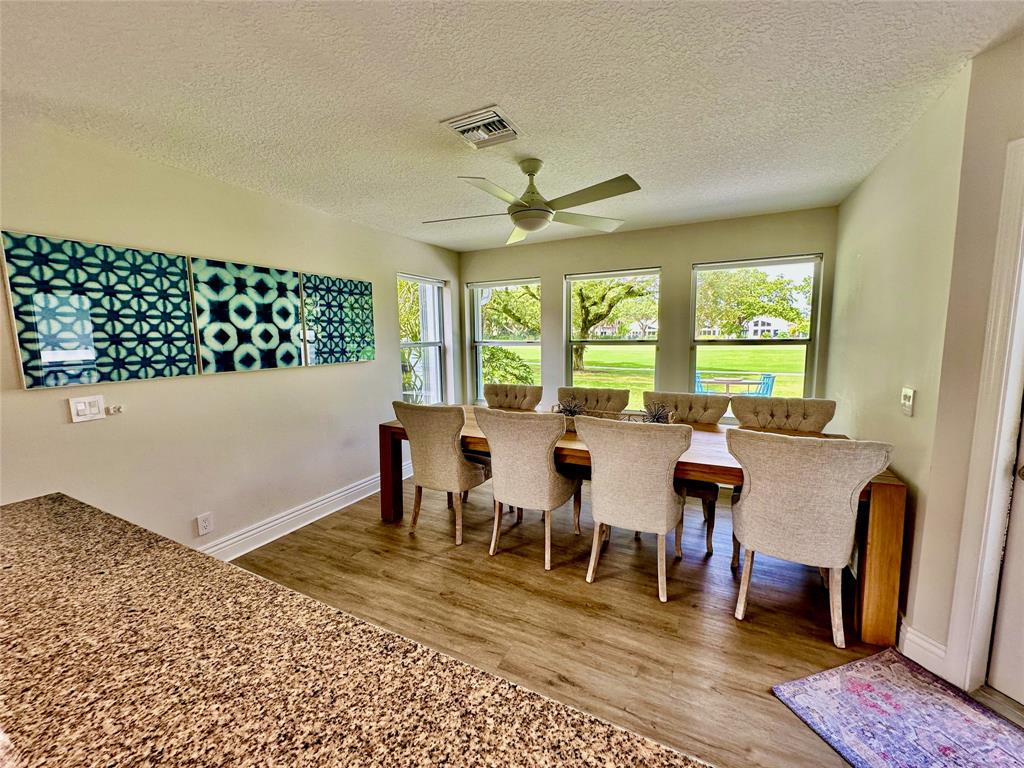 2295 Northwest 53rd Street Boca Raton, FL 33496 - Photo 13 of 89 a dining room with wooden floor a chandelier a wooden table and chairs