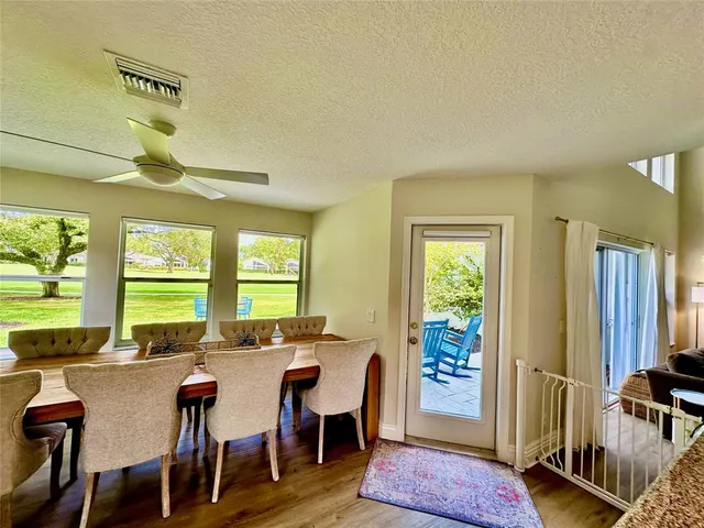 a kitchen with stainless steel appliances granite countertop a stove top oven a sink a dining table and chairs with wooden floor