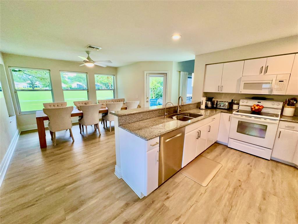 2295 Northwest 53rd Street Boca Raton, FL 33496 - Photo 25 of 89 a kitchen with stainless steel appliances granite countertop a stove top oven a sink a dining table and chairs with wooden floor