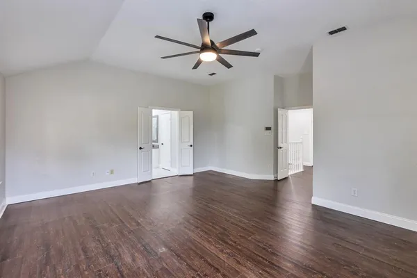 an empty room with wooden floor ceiling fan and window