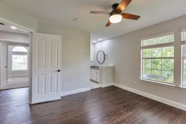 a view of empty room with wooden floor and fan