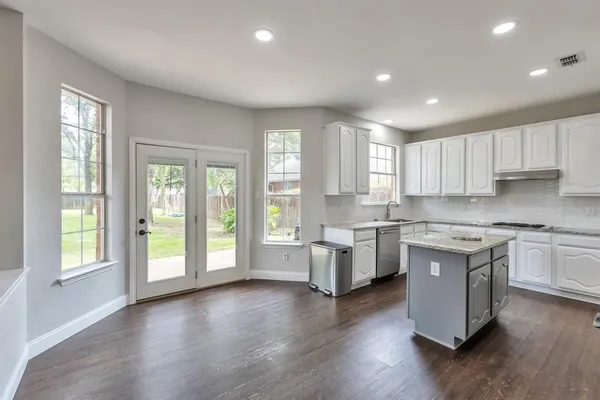 a kitchen with granite countertop a stove top oven sink and cabinets