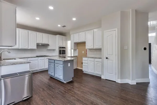 a large kitchen with stainless steel appliances granite countertop a stove a sink and white cabinets