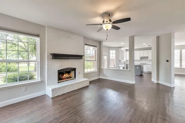 a view of an empty room with wooden floor fireplace and a window