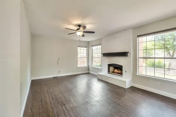 an empty room with windows fireplace and wooden floor