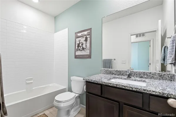 a bathroom with a granite countertop toilet a sink and a bathtub