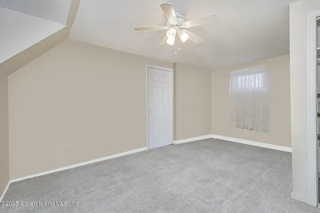 an empty room with a window and a ceiling fan