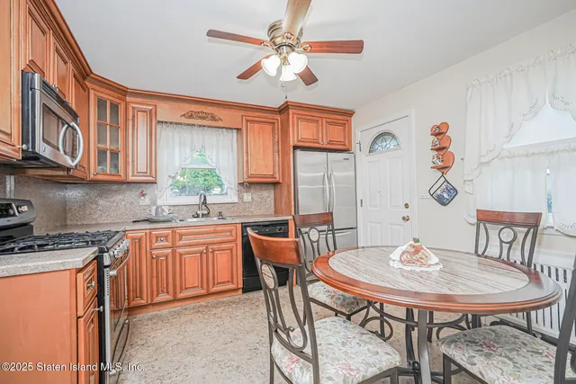 a kitchen with stainless steel appliances granite countertop a dining table chairs and a refrigerator