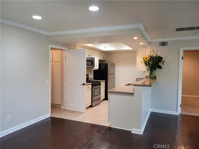 a view of an empty room with a kitchen and wooden floor