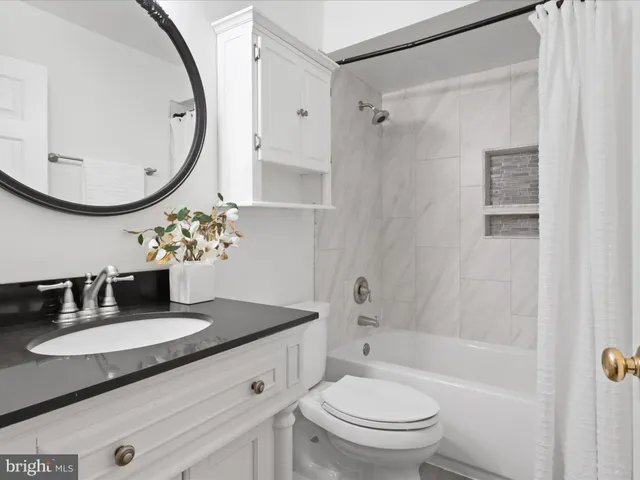 a bathroom with a granite countertop sink a toilet and a mirror