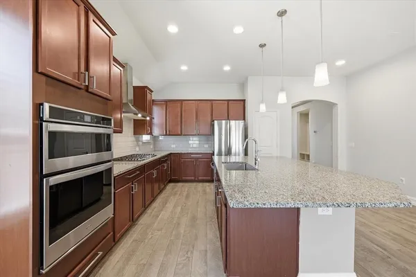 a large kitchen with stainless steel appliances granite countertop a stove a sink and a refrigerator