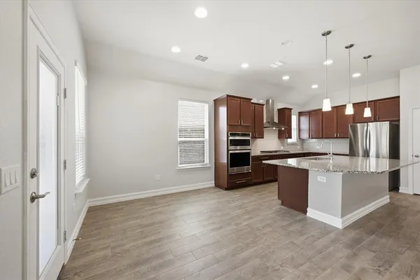 a kitchen with stainless steel appliances kitchen island granite countertop a refrigerator and a stove top oven