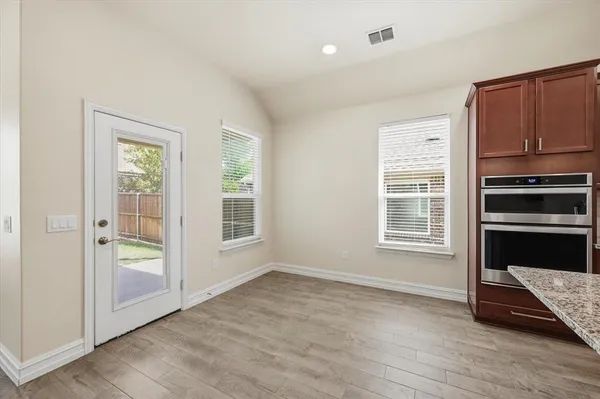 an empty room with wooden floor cabinet and windows