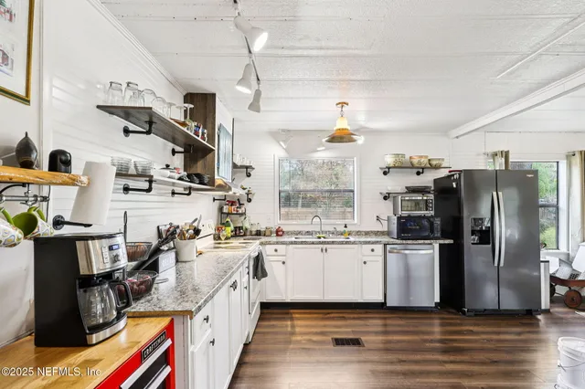 a kitchen with stainless steel appliances a refrigerator a sink a stove and wooden floors
