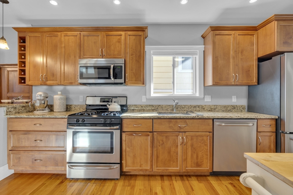 173 Train Street, Unit 1 Boston, MA 02122 - Photo 5 of 13 a kitchen with granite countertop wooden cabinets stainless steel appliances and a window