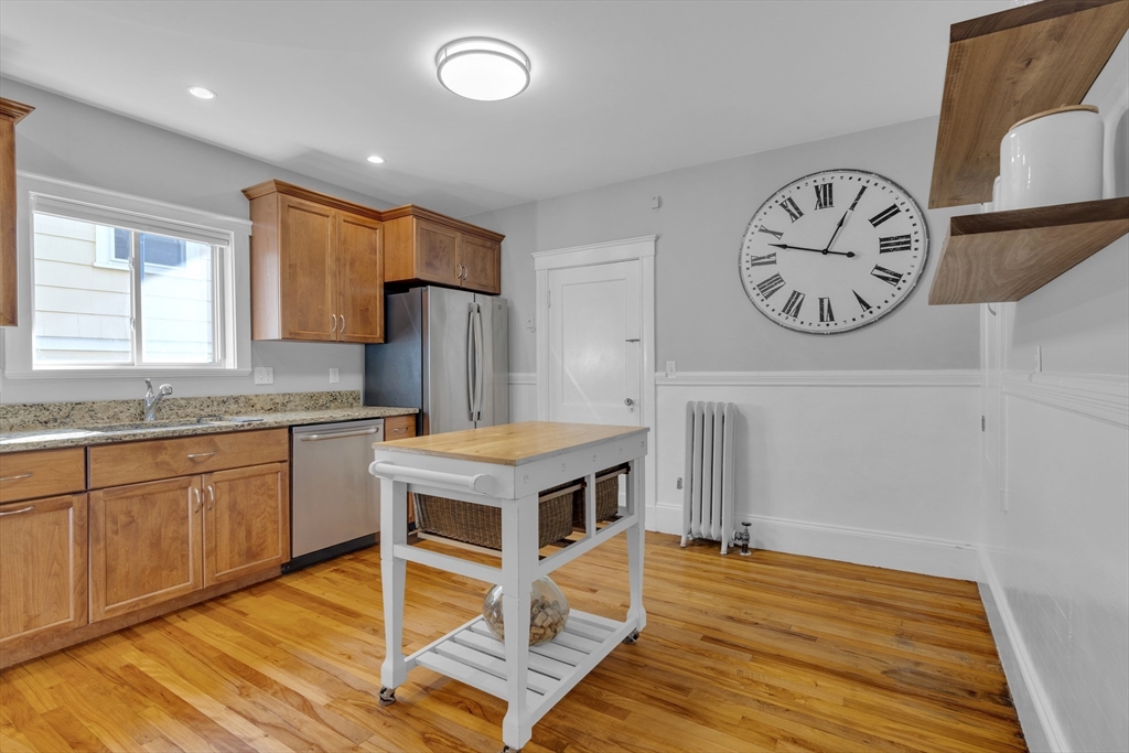 173 Train Street, Unit 1 Boston, MA 02122 - Photo 6 of 13 a kitchen with kitchen island granite countertop a stove cabinets and wooden floor