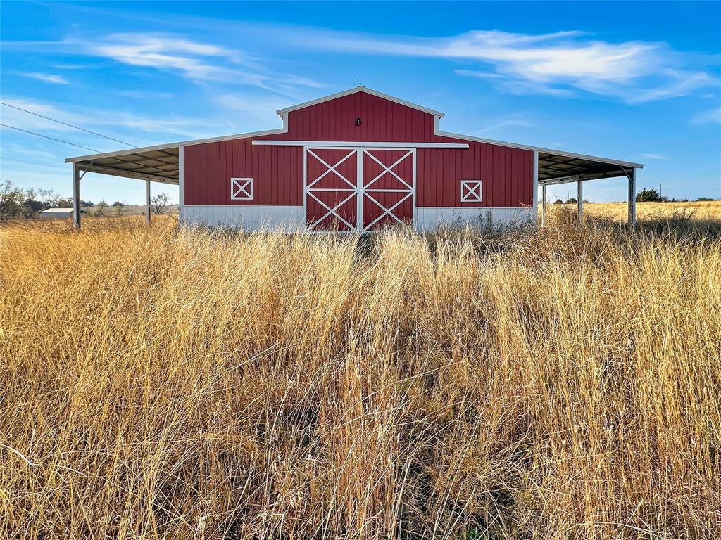 501 County Road 501 Blue Ridge, TX 75424 - Photo 1 of 27 Full exterior view showcasing the barn’s symmetrical design, metal roof, and extended covered lean-tos on both sides for additional sheltered space.