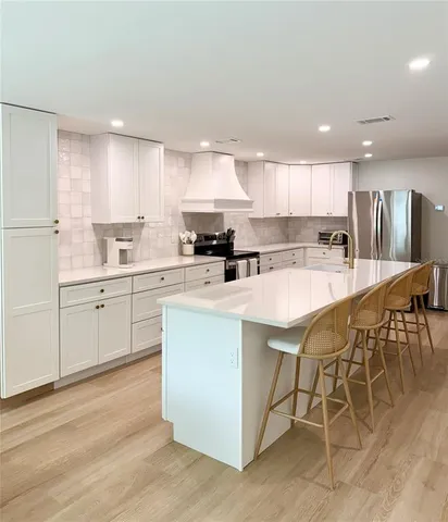 a kitchen with stainless steel appliances kitchen island granite countertop a sink a stove a dining table and chairs