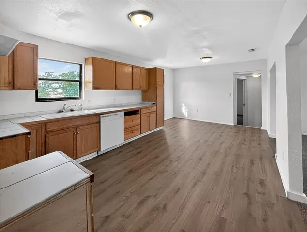 a kitchen with a sink a stove cabinets and wooden floor