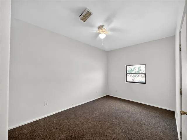 an empty room with a window and ceiling fan