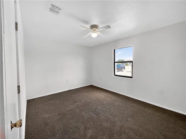 an empty room with a window and a ceiling fan