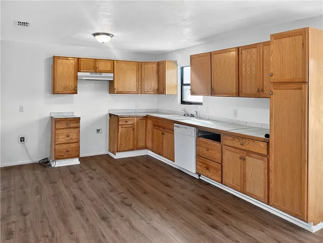 a kitchen with stainless steel appliances granite countertop a sink cabinets and wooden floor