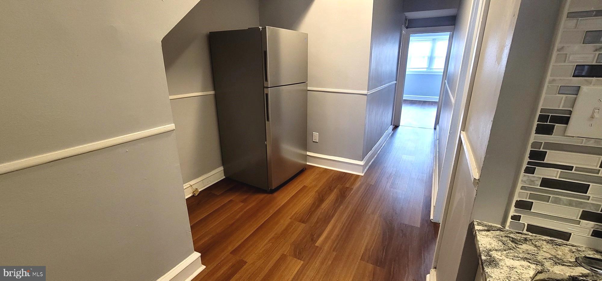 4922 North 8th Street Philadelphia, PA 19120 - Photo 7 of 21 a view of a refrigerator in kitchen and an empty room with wooden floor