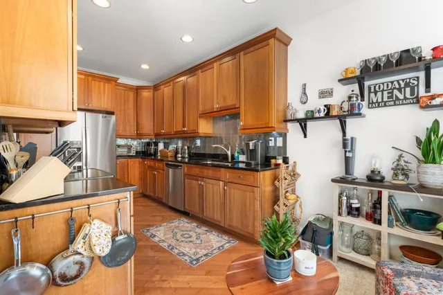 a kitchen with stainless steel appliances granite countertop a refrigerator a stove a sink dishwasher and cabinets with wooden floor