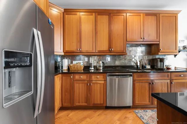 a kitchen with stainless steel appliances granite countertop a refrigerator a stove and a sink with wooden floor