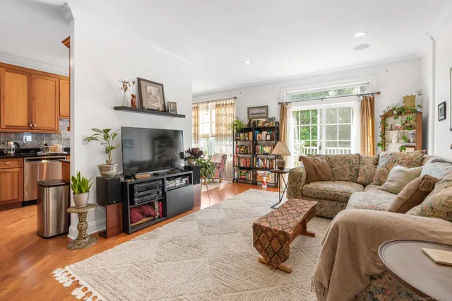a living room with furniture a flat screen tv and a refrigerator