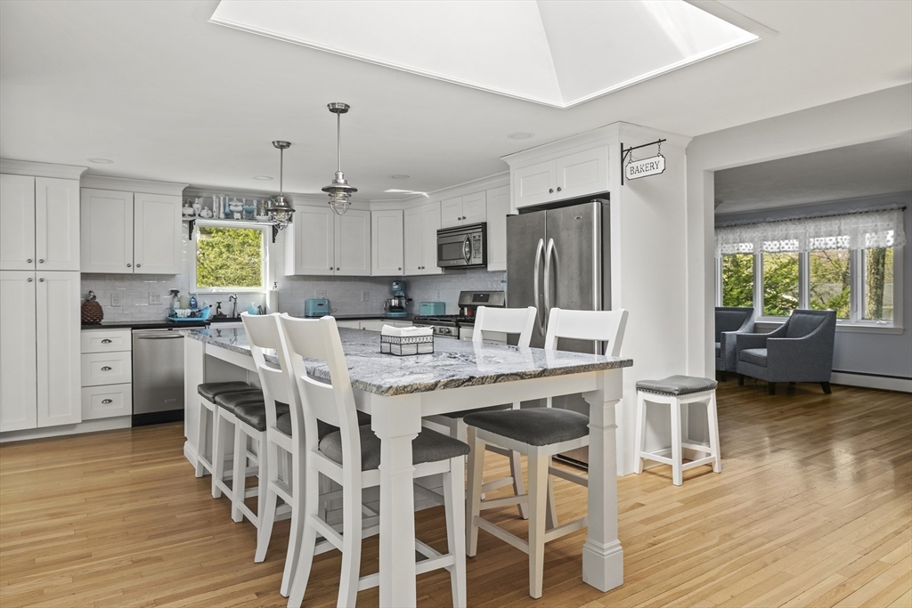 21 Reading Terrace Reading, MA 01867 - Photo 2 of 42 a kitchen with stainless steel appliances granite countertop a dining table chairs refrigerator and sink