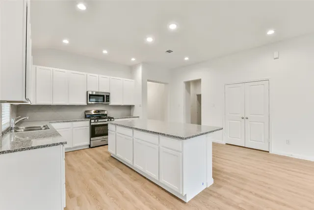a kitchen with stainless steel appliances granite countertop a sink and a stove top oven