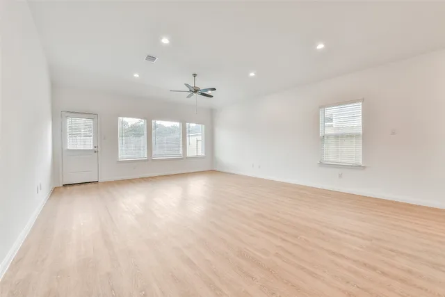 an empty room with wooden floor and windows
