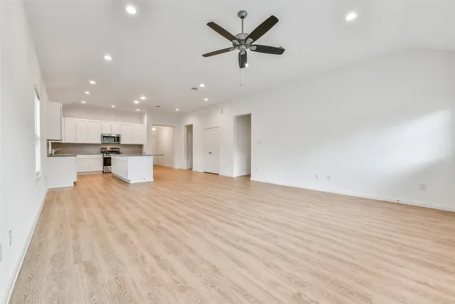 a view of kitchen with kitchen island a sink wooden floor and a refrigerator