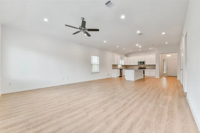 a view of empty room with wooden floor and windows
