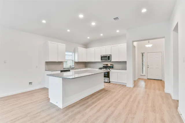 a kitchen with white cabinets and appliances