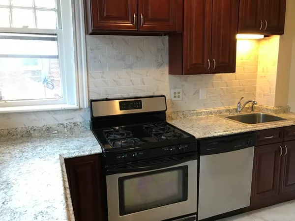 a kitchen with granite countertop a stove sink and cabinets