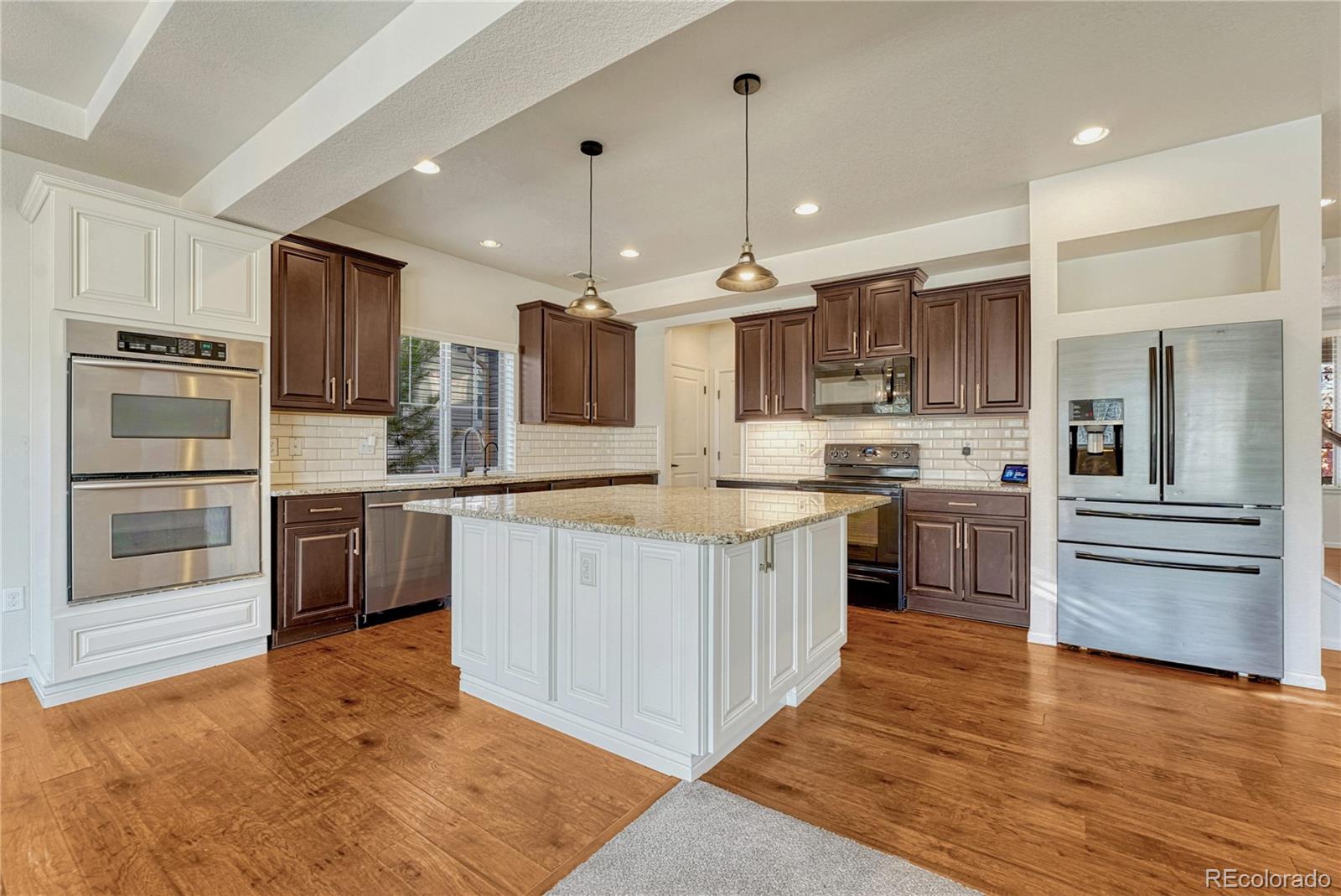 3359 Starry Night Loop Castle Rock, CO 80109 - Photo 7 of 47 a large kitchen with stainless steel appliances granite countertop a refrigerator stove a sink and a microwave