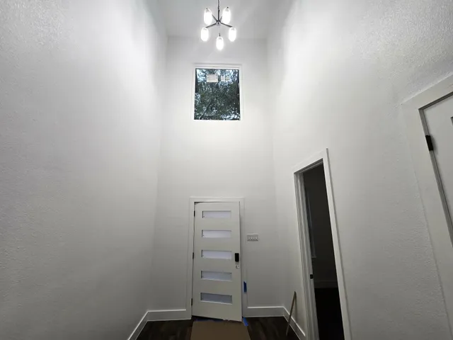 an empty room with wooden floor cabinet and windows