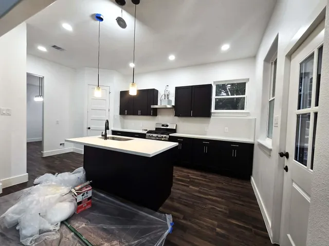 a large kitchen with stainless steel appliances a stove center island a sink dishwasher and a flat screen tv