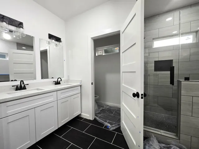 a bathroom with a double vanity sink a mirror and a shower