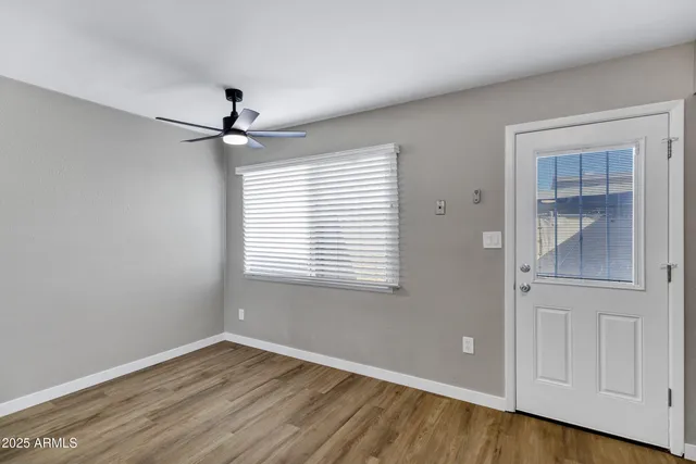 a view of an empty room with wooden floor and a window