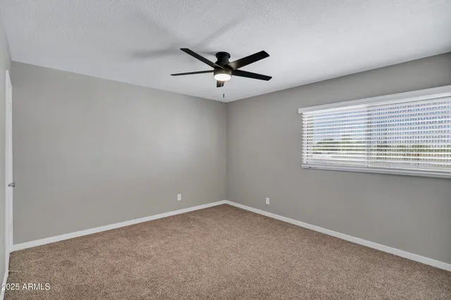 an empty room with a window and a ceiling fan