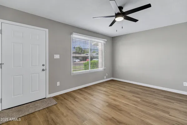 a view of an empty room with window and a ceiling fan