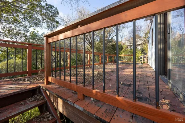 a balcony with wooden floor and trees in the back